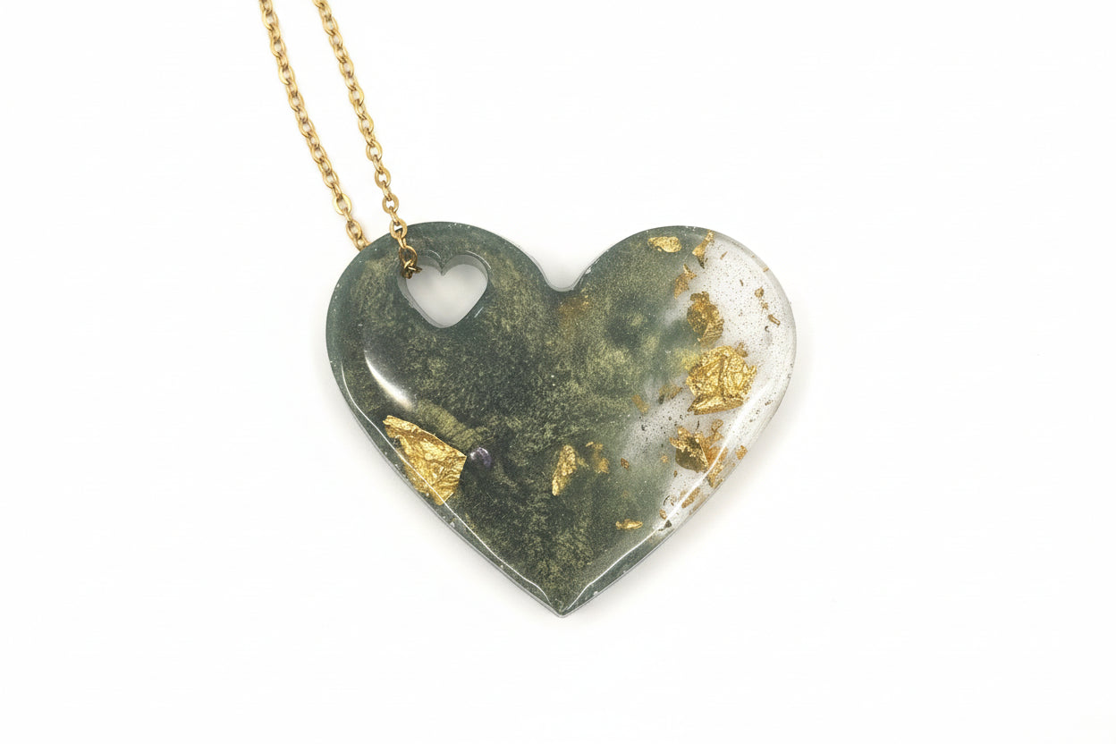 Heart-shaped pendant with gold accents on a chain against a light gray background